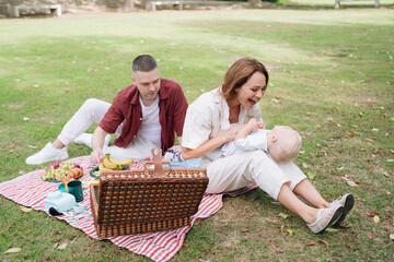 Family enjoying picnic in park together with baby