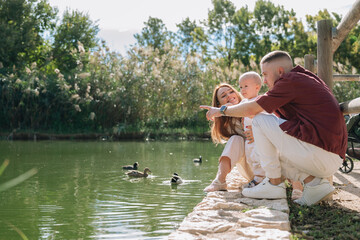 Family playing with baby watching ducks in park