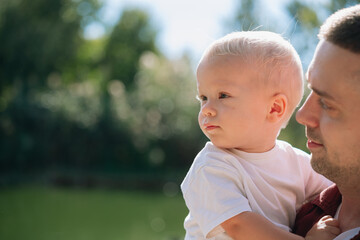 Father holding young son outdoors, enjoying bright sunny day