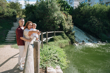 Happy family with baby pointing near park waterfall