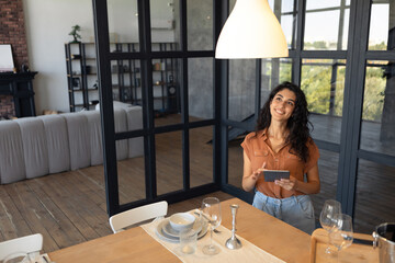 Modern technologies in daily life. Portraif of happy young woman using digital tablet at kitchen, copy space. Millennial lady browsing social media or having online video call at home