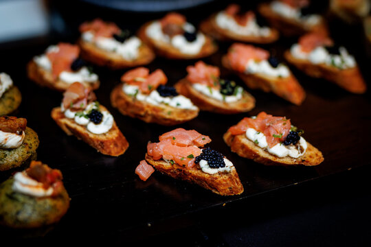 Salmon and caviar canap&eacute;s arranged on dark serving tray