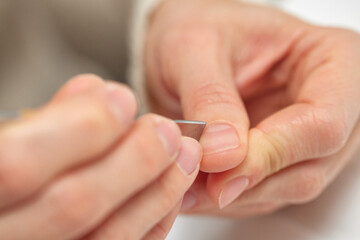 Person using a metal tool pushing back cuticles on finger for nail care
