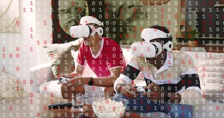 Playing two adults wearing white VR headsets and holding controllers at home on sofa with popcorn