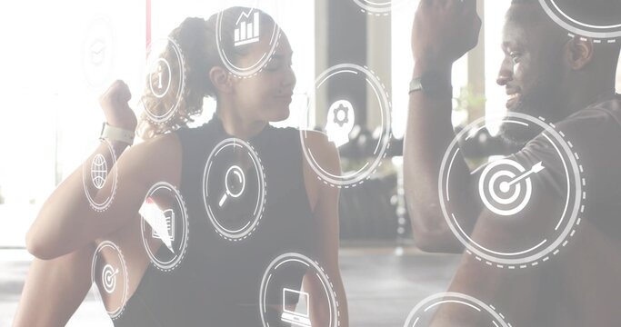 High-fiving woman and man fitness partners wearing workout gear on gym floor, digital icons - Powered by Adobe