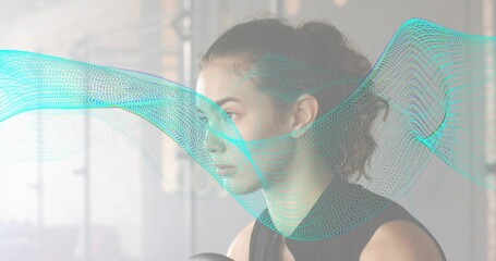 Resting woman in black tank top holding fitness ball in studio with turquoise wave, windows, frame