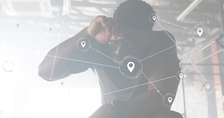 Leaning man in dark tee raising forearm to forehead in warehouse, with digital map overlay