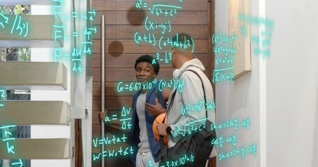 Leaning student in dark jacket gesturing in entry, holding basketball with teal equations on glass