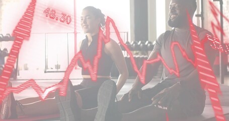 Stretching workout partners in gymwear extending legs on mats in gym, showing red ECG overlay