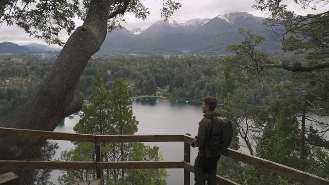 Male photographer taking pictures of the mountain landscape and the tranquil waters of Bahia Mansa from a scenic overlook in Villa La Angostura, Neuqu&eacute;n