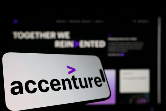 Kiel, Germany - 01-12-2026: Smartphone displaying Accenture logo in front of the company website on a monitor