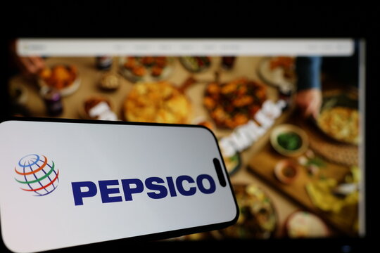 Kiel, Germany - 01-12-2026: Smartphone displaying Pepsico logo in front of the company website on a monitor