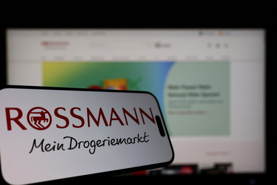 Kiel, Germany - 01-12-2026: Smartphone displaying Rossmann logo in front of the company website on a monitor