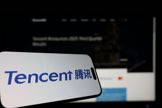 Kiel, Germany - 01-12-2026: Smartphone displaying Tencent Holdings logo in front of the company website on a monitor