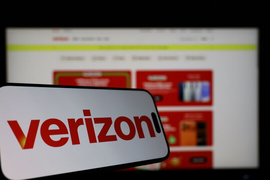 Kiel, Germany - 01-12-2026: Smartphone displaying Verizon logo in front of the company website on a monitor
