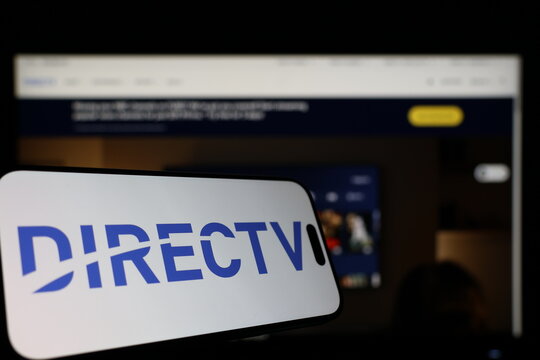 Kiel, Germany - 01-12-2026: Smartphone displaying DIRECTV logo in front of the company website on a monitor
