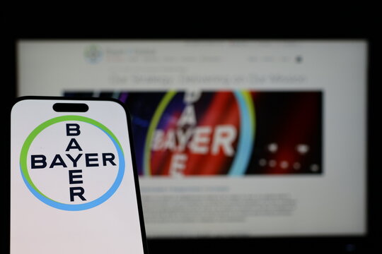 Kiel, Germany - 01-12-2026: Smartphone displaying Bayer logo in front of the company website on a monitor