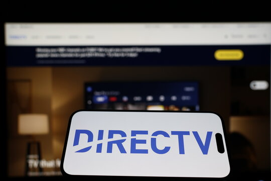 Kiel, Germany - 01-12-2026: Smartphone displaying DIRECTV logo in front of the company website on a monitor