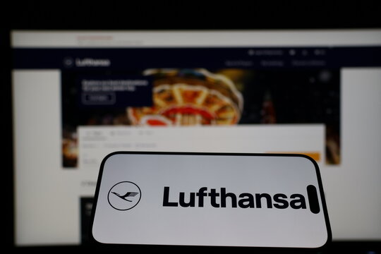 Kiel, Germany - 01-12-2026: Smartphone displaying Lufthansa logo in front of the company website on a monitor