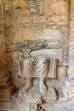 View of an ancient stone carving of draped fabric rests against a weathered brick wall, revealing the textures of history, Taxila, Khyber Pakhtunkhwa, Pakistan.