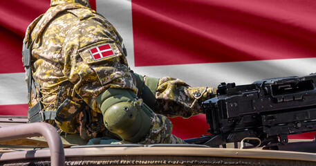 Denmark flag with soldier at machine gun turret in front of it. Closeup side view.