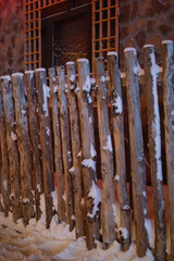 Winter icicles hanging from an old wooden fence and roof in a snowy forest scene at Xuexiang China snow town.