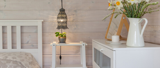 Panoramic cozy Scandinavian bedroom interior banner with warm pendant lamp, candle and spring...