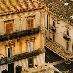 Historic Urban Architecture In Ragusa, Sicily: Weathered Stone Buildings, Narrow Streets, Layered Rooftops, And Church Dome Forming Dense Mediterranean Cityscape