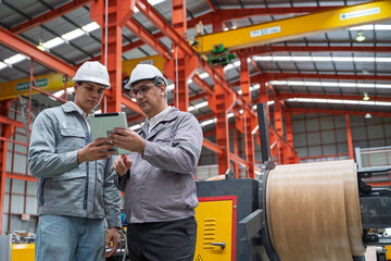Engineers inspecting equipment and discussing maintenance procedures inside a modern industrial factory. Safety, teamwork, and production quality control in a manufacturing plant.