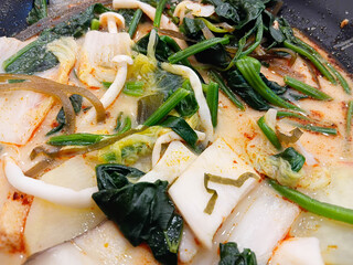 Spicy mala soup served in a black bowl, filled with vegetables and herbs, rich chili broth, hot flavor, Asian comfort food style.