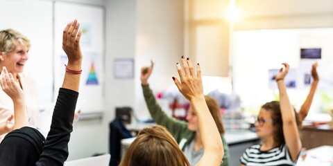 A diverse classroom with students raising hands, engaging in learning. Bright classroom, eager students, active participation, hands raised, education focus. Girls raising hands in classroom.