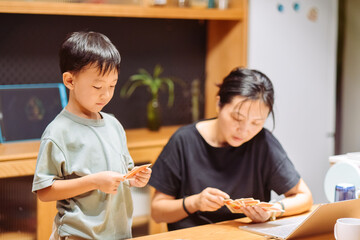 Asian mother and seven-year-old son playing card games together in a cozy home indoor setting