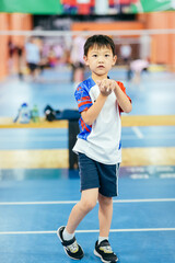 Seven-year-old Asian boy doing warm-up exercises on an indoor badminton court