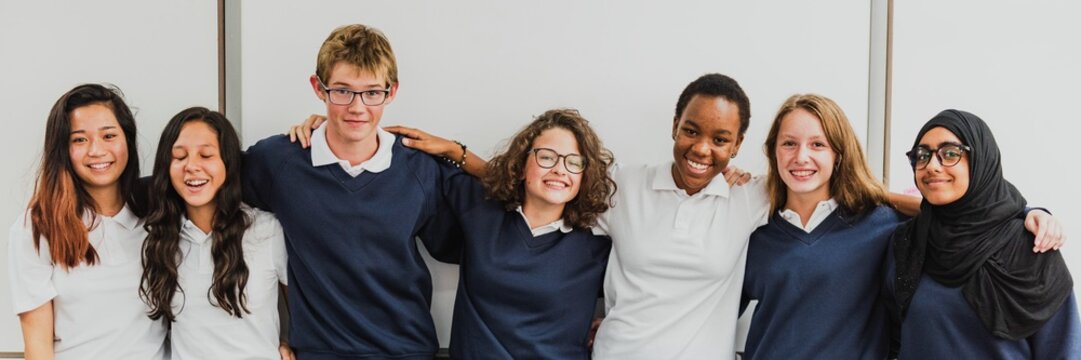 Group of diverse students in uniforms smiling. Diverse group of students in blue and white uniforms. Happy students, diverse and smiling in school uniforms. Diverse international high school students.