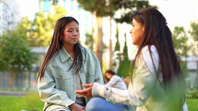 Asian girlfriends talking and gossiping in a city park