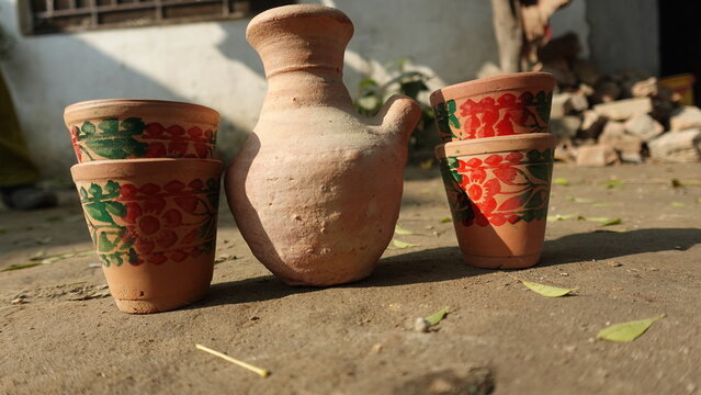 Traditional Hand-Painted Clay Pottery Cups and Water Jug on the Ground in a Rural Village