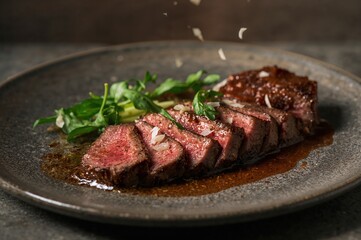 Perfect tagliata slices fan across stone plate beneath falling arugula and delicate Parmesan