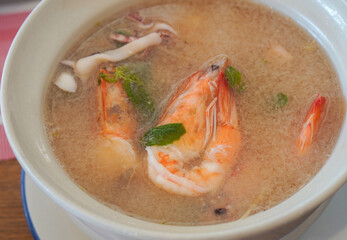 top view Seafood tom yum with clear soup in a ceramic cup on a galvanized plate on table background, food, eat, object, copy space