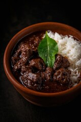 Moody Indonesian beef rendang served with rice in traditional clay bowl