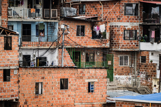 View of vibrant red brick buildings stacked high, a maze of windows and balconies catching the light, clotheslines strung between, in Comuna 13, Medellin, Colombia.