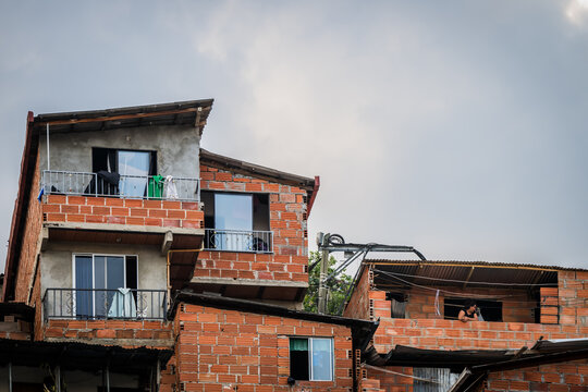 View of vibrant red brick houses stacked precariously against the cloudy sky create a unique urban landscape, Comuna 13, Medellin, Colombia.
