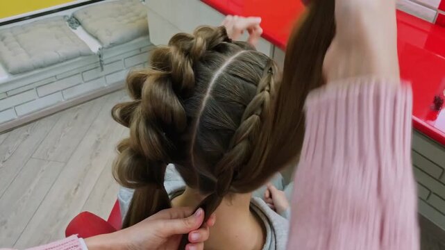 Process of creating a voluminous pull-through braid hairstyle for a young girl