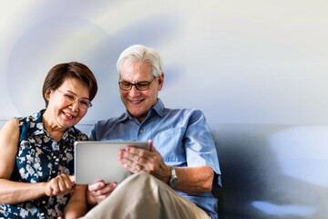 Senior couple using a digital device in a living room