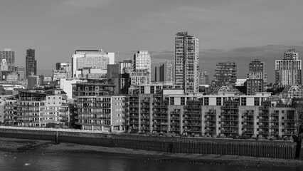 London urban dwellings and skyscrapers lining the River Thames in black and white