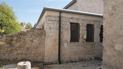 Ancient stone building with arched windows and intricate masonry under a bright blue sky.