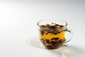 Flower tea in a glass cup on white glass with shadow, selective focus.