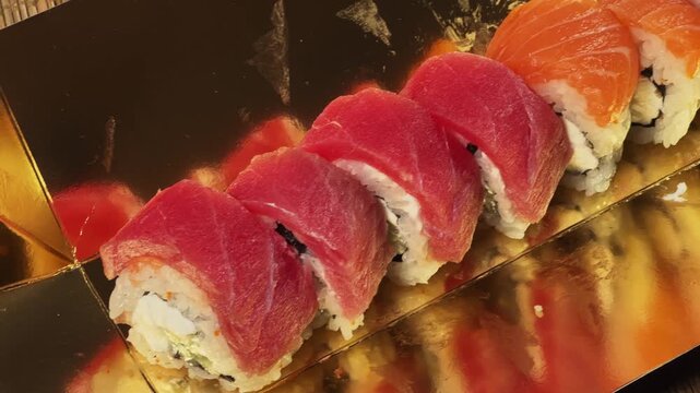 Sushi rolls uramaki with salmon and tuna in golden packaging
