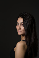 A woman with black hair wakes up in the morning in a white blanket and catches the rays of the sun. The portrait is creative, with brown eyes. High quality photo