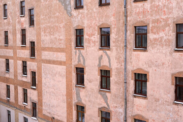 Obraz premium Vintage apartment building facade with repetitive windows and cracked plaster texture
