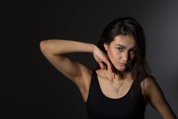 A woman with black hair wakes up in the morning in a white blanket and catches the rays of the sun. The portrait is creative, with brown eyes. High quality photo